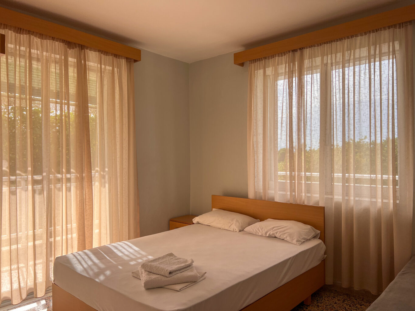 Bright hotel room with a double bed , featuring large windows and natural light