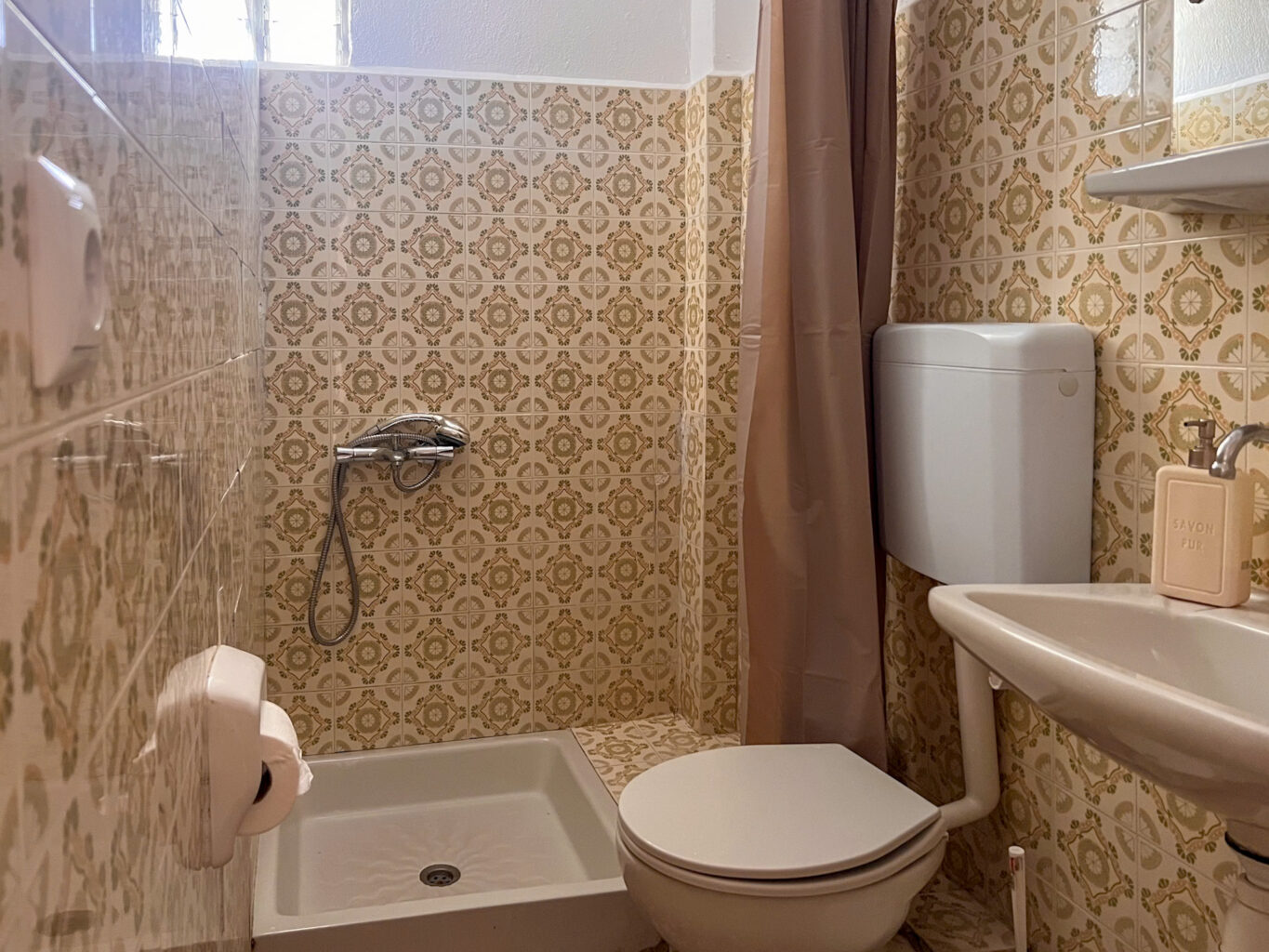 Compact bathroom with vintage tile design, a shower, toilet, and sink