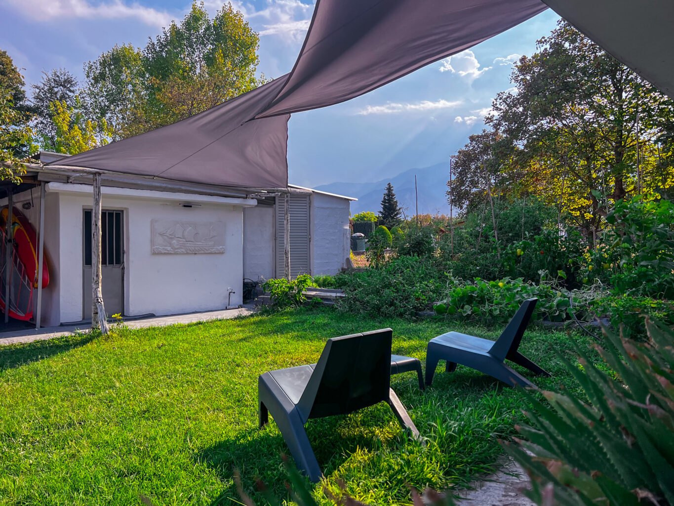 Outdoor garden area with relaxation chairs, shade canopy, and a view of the mountains in the background