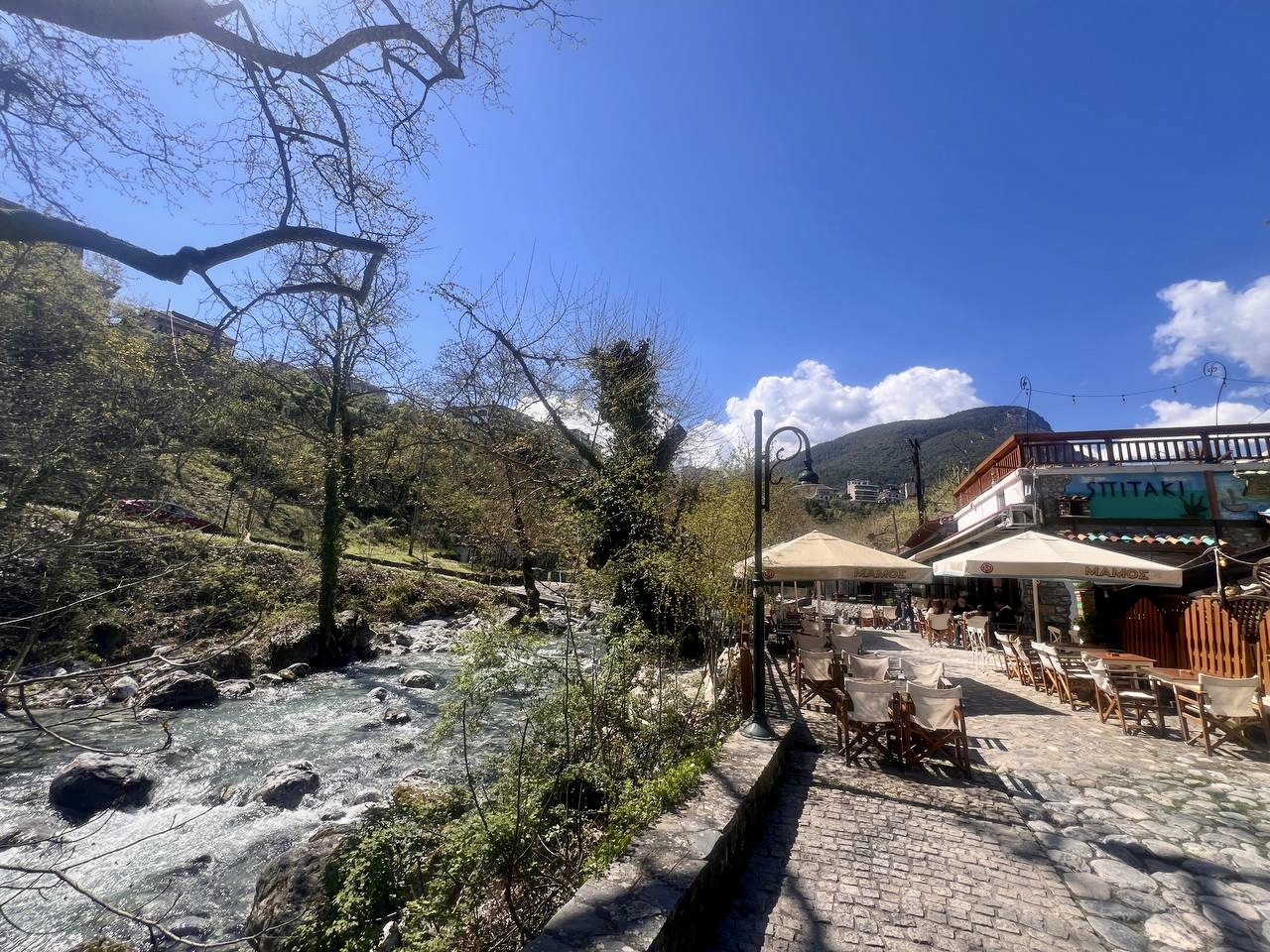 Enipeas river flowing through Litochoro with riverside cafes and Mount Olympus in the background