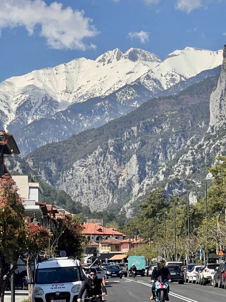 View of Litochoro main street with snow-capped Mount Olympus towering above the town in spring